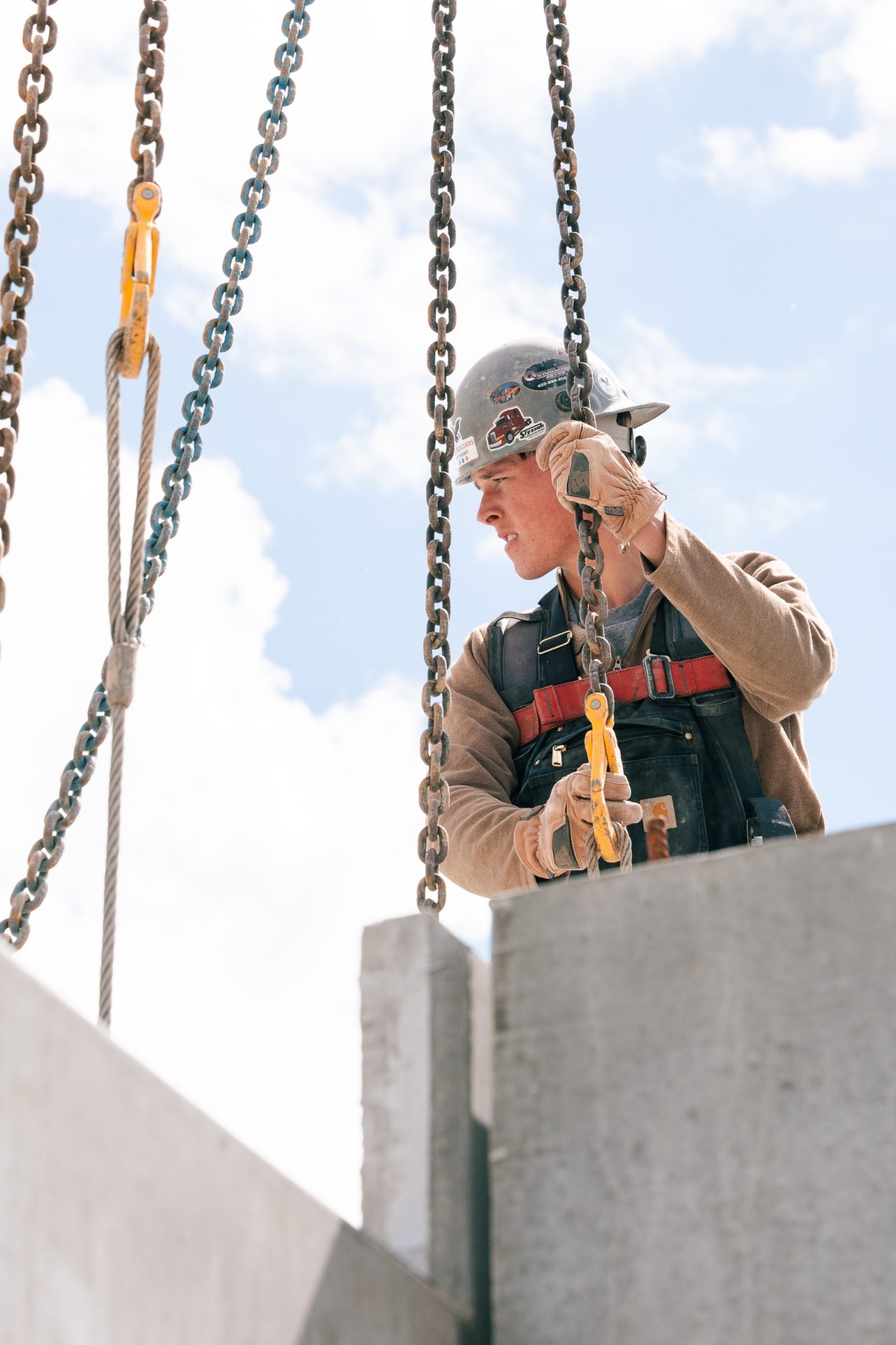 An Eagle Builder worker looking to his right side while holding a chain attached to a concrete panel