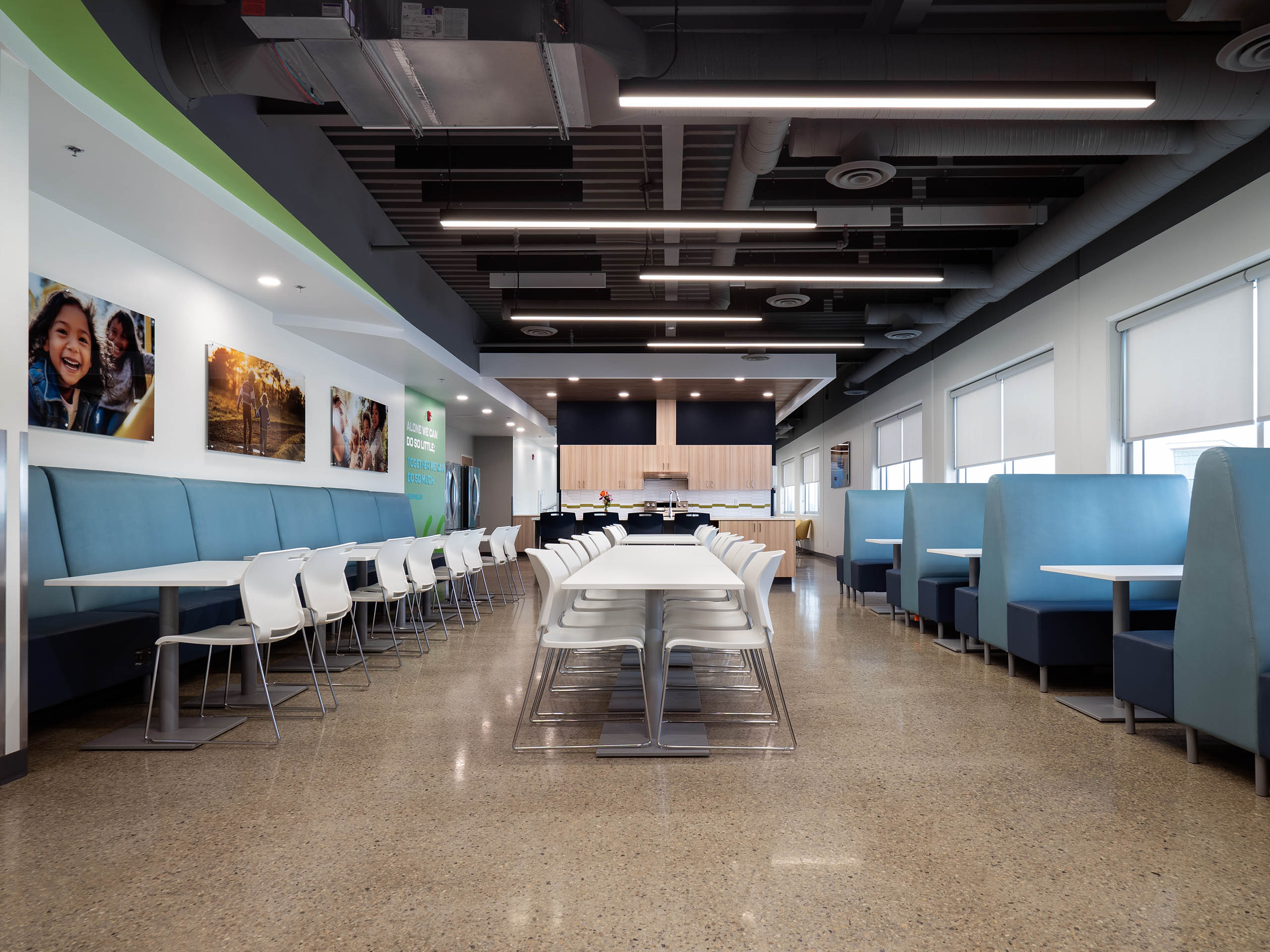 Kitchen and dining area with a black ceiling, white tables and chairs, along with blue chairs