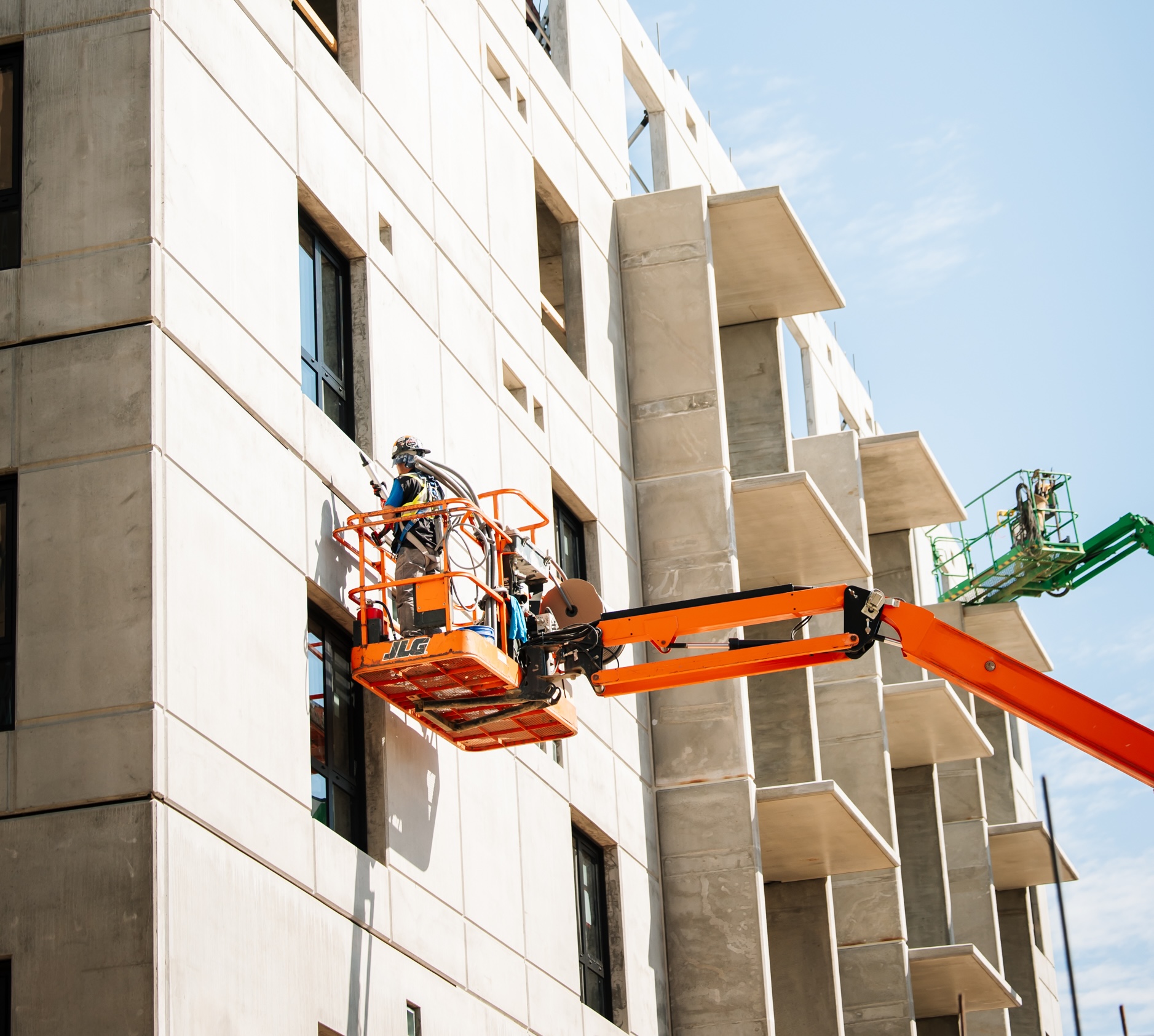 An Eagle Builder worker on a crane platform at the side of a concrete building